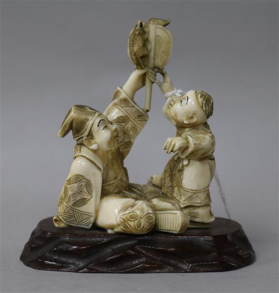 A Japanese Meiji carved ivory group, father and son, on carved hardwood base height 10cm